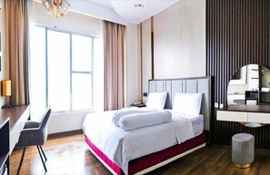 Ein Hotelzimmer mit Bett, Nachttisch, Stuhl, Schreibtisch und einem großen Fenster.