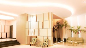 A modern lobby with a curved wall, a reception desk, seating area, and palm trees.
