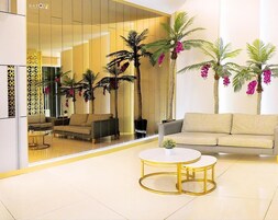 Una sala moderna con un sofá, dos mesas redondas y plantas decorativas.