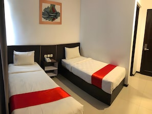 A hotel room with two single beds, a nightstand, a telephone, and a painting on the wall. - Hotel Sg17 Tuban (Tuban)