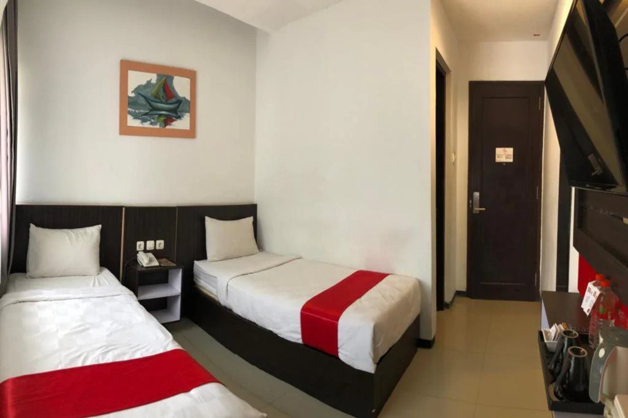 A hotel room with two beds, a nightstand, a telephone, and a painting on the wall.