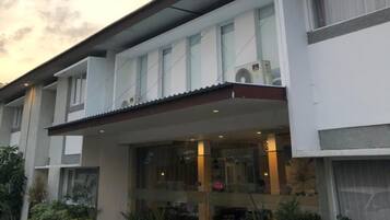 A modern two-story building with a flat roof, large windows, and a visible air conditioning unit.