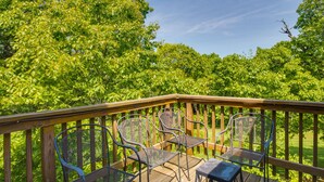 A wooden deck with metal chairs and a table, surrounded by lush green trees. - Wintergreen Resort Vacation Rental w/ Pool Access! (Wintergreen Resort)