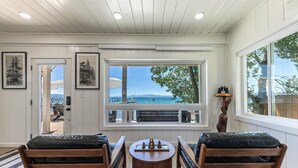 Una habitación con vista al mar, un banco de madera, una mesita y un atril decorativo de madera.