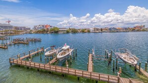 Un port de plaisance où plusieurs bateaux sont amarrés à des quais en bois, entouré d’une eau calme et sous un ciel dégagé.