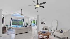 A spacious living room with a large window, a ceiling fan, and a pool view. - Wonderful Heated Pool House Delray Beach near Ocean - close to shops and the av’ (Delray Beach)