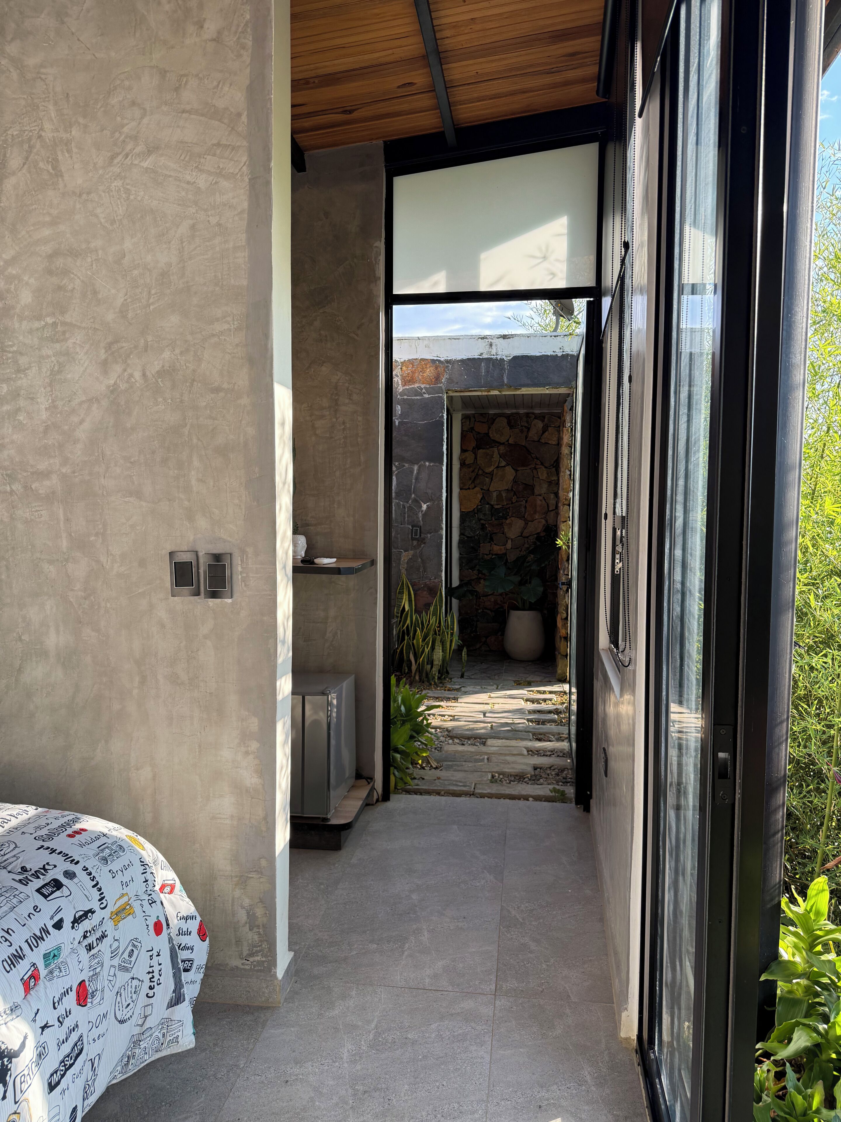 A modern interior with a concrete wall, a stone wall, and a glass door leading outside.