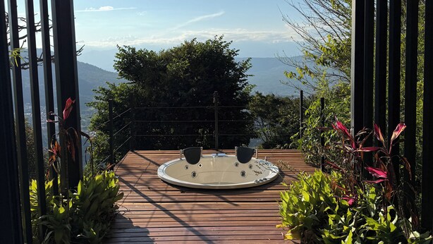 A hot tub on a wooden deck with a view of mountains and a clear sky. - Sunset Palm Alojamiento Rural (San Gil)