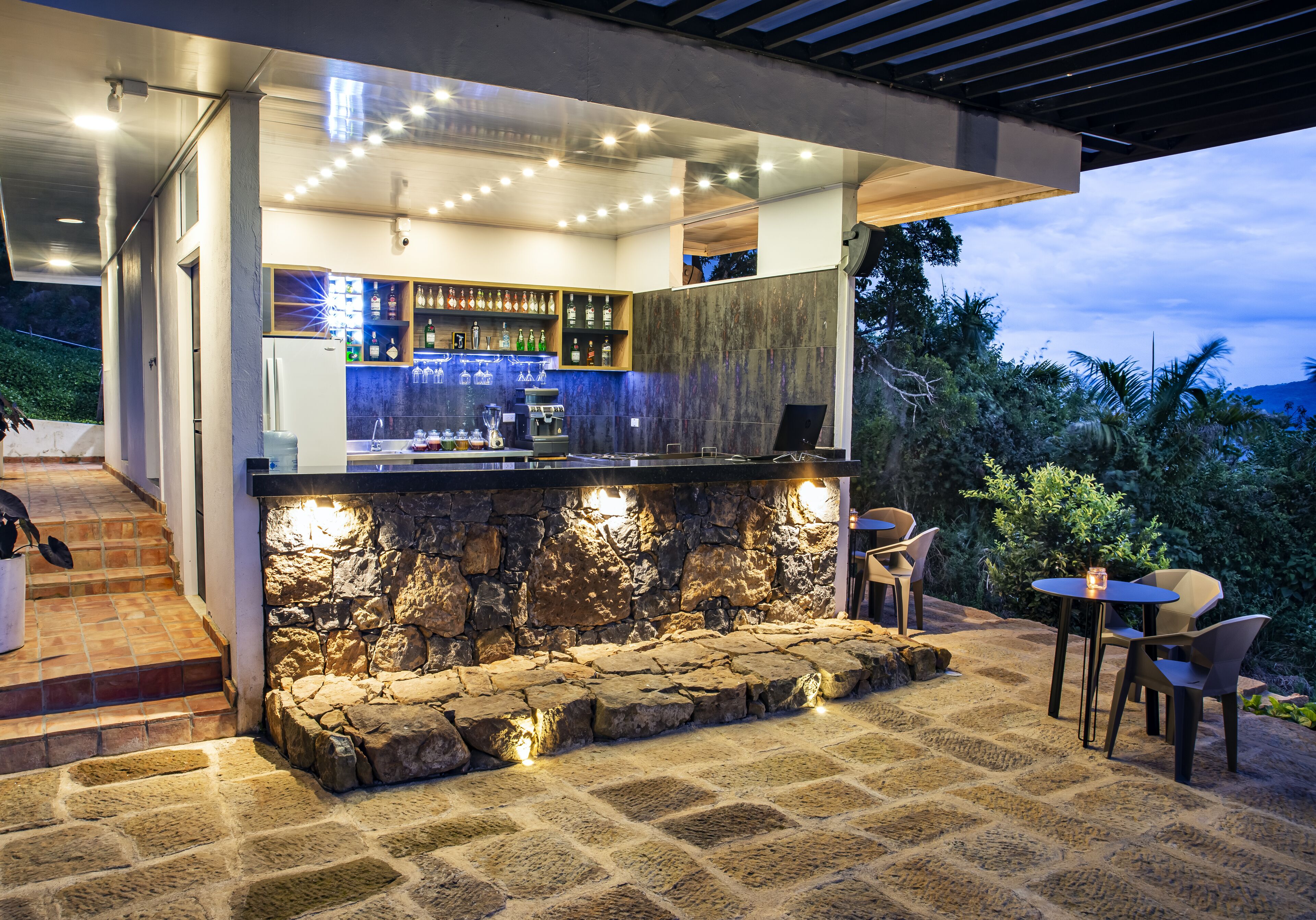 Un área de bar al aire libre con asientos de piedra, una barra y vistas del paisaje circundante.