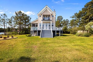 A two-story house with a front porch, a staircase leading to the entrance, and a surrounding grassy area.