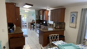 A spacious kitchen with wooden cabinets, a granite countertop, and a dining area with a glass table.