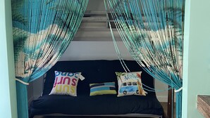 A hammock bed with a sign above reading 'BEACH HOUSE' and pillows with text.