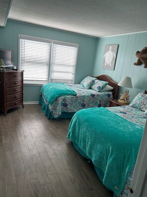 Relax in this nautical-themed room with two beds, a dresser, and a TV.