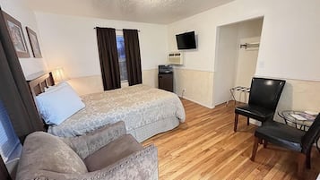 A hotel room with two beds, a desk, a chair, a TV, and a small table.