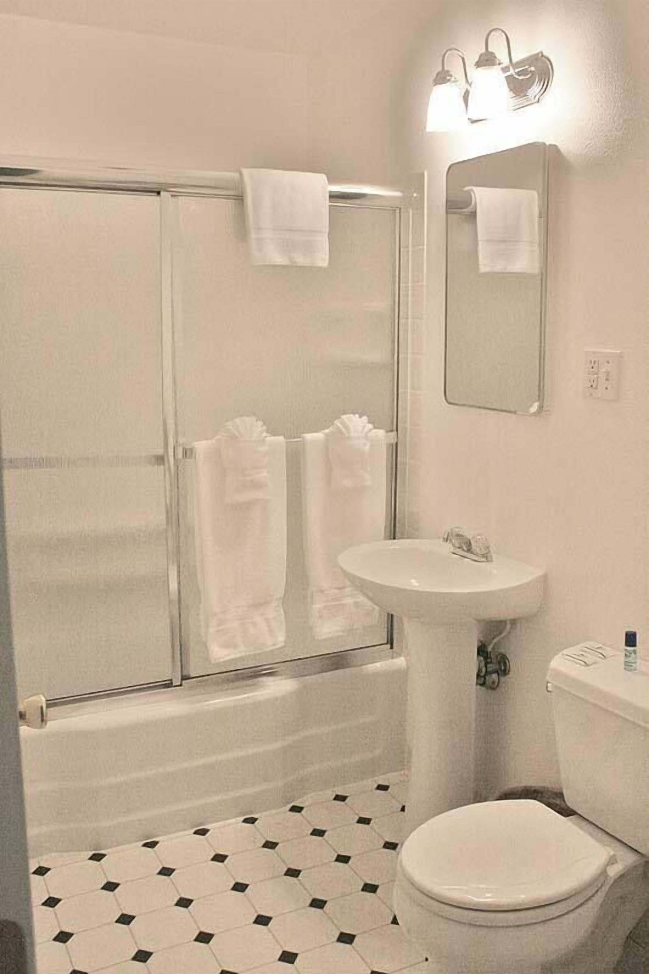 A bathroom with a bathtub, a sink, a toilet, and a glass shower enclosure.