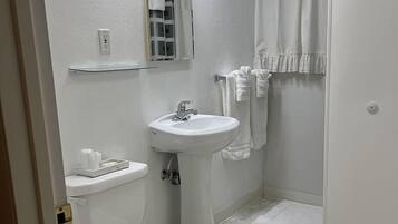 A bathroom with a toilet, sink, and shower.