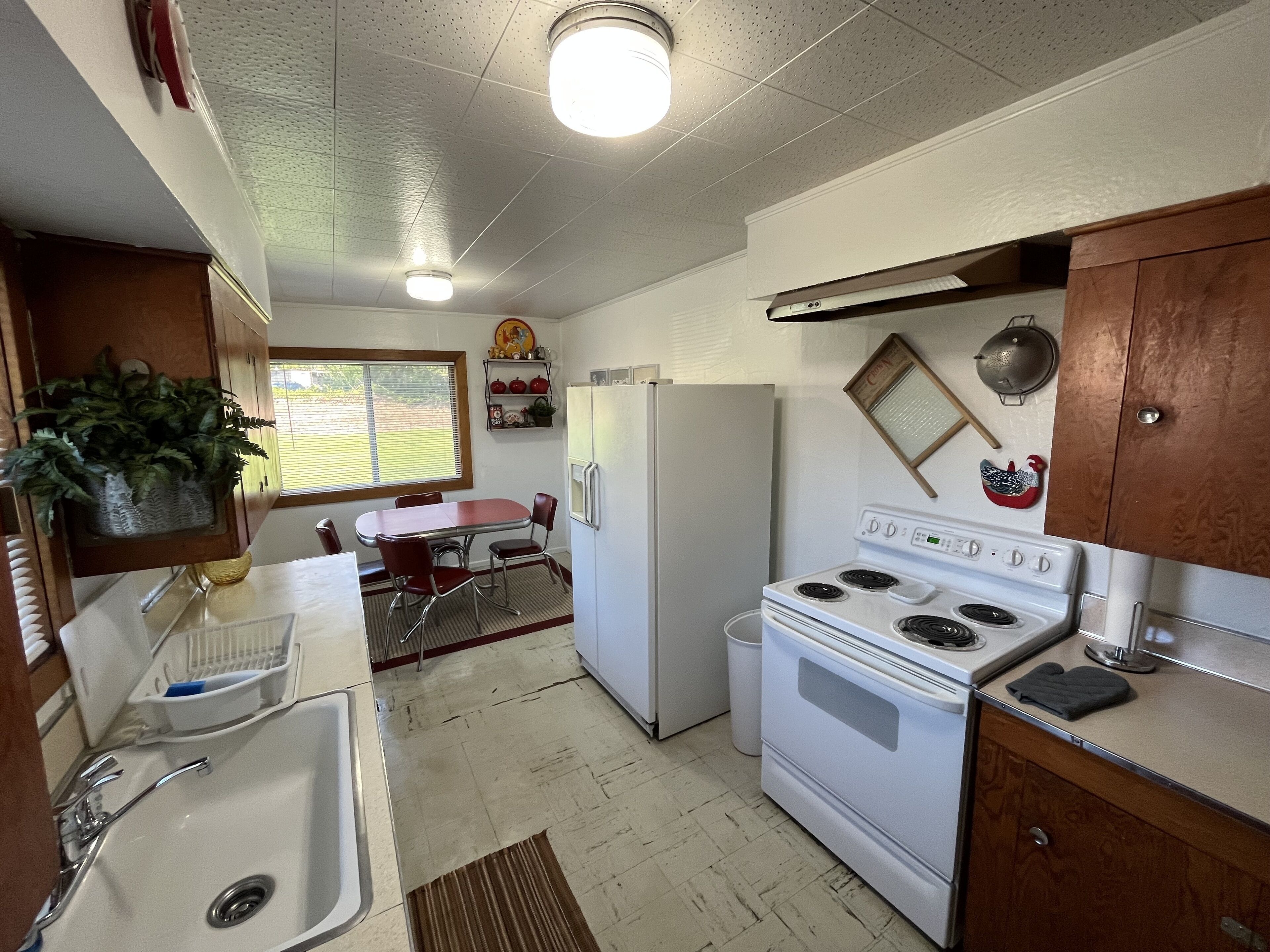 Una cocina compacta con refrigerador, estufa, pileta y muebles de madera.