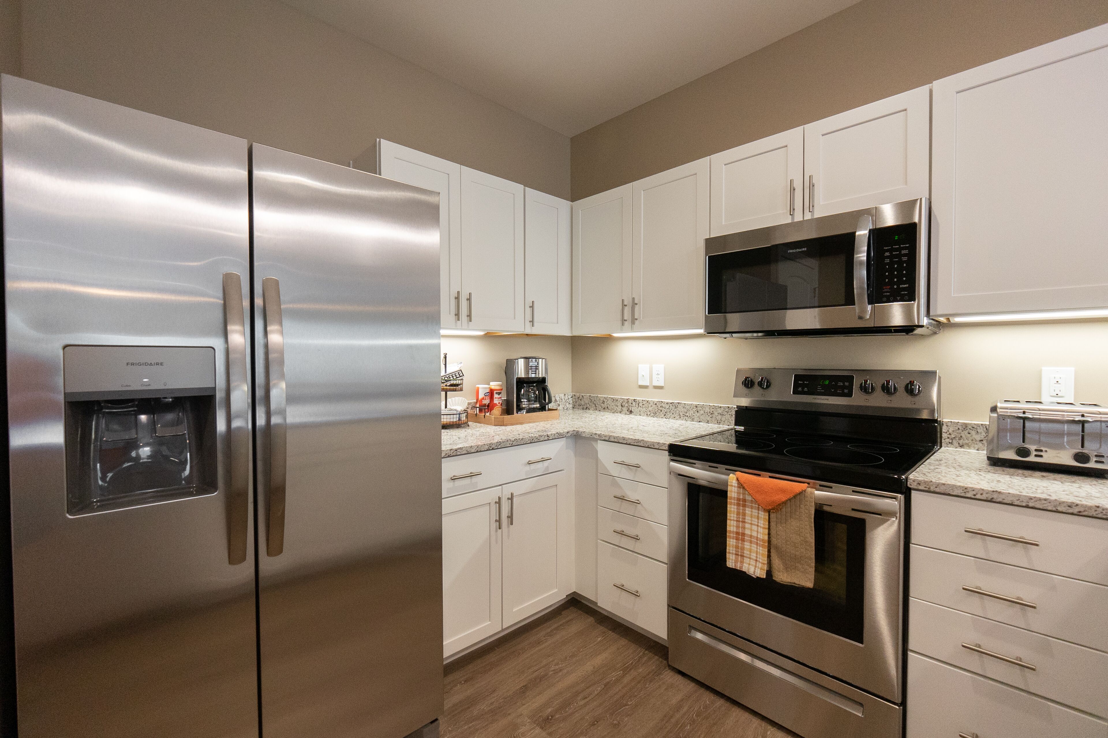 A modern kitchen with stainless steel appliances, white cabinets, and a granite countertop.