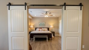 A bedroom with a bed, bedside lamps, a bench, and a ceiling fan. - New Build Walk-In 3BR Branson Condo w/ Indoor Pool | (FH-G203) (Branson)