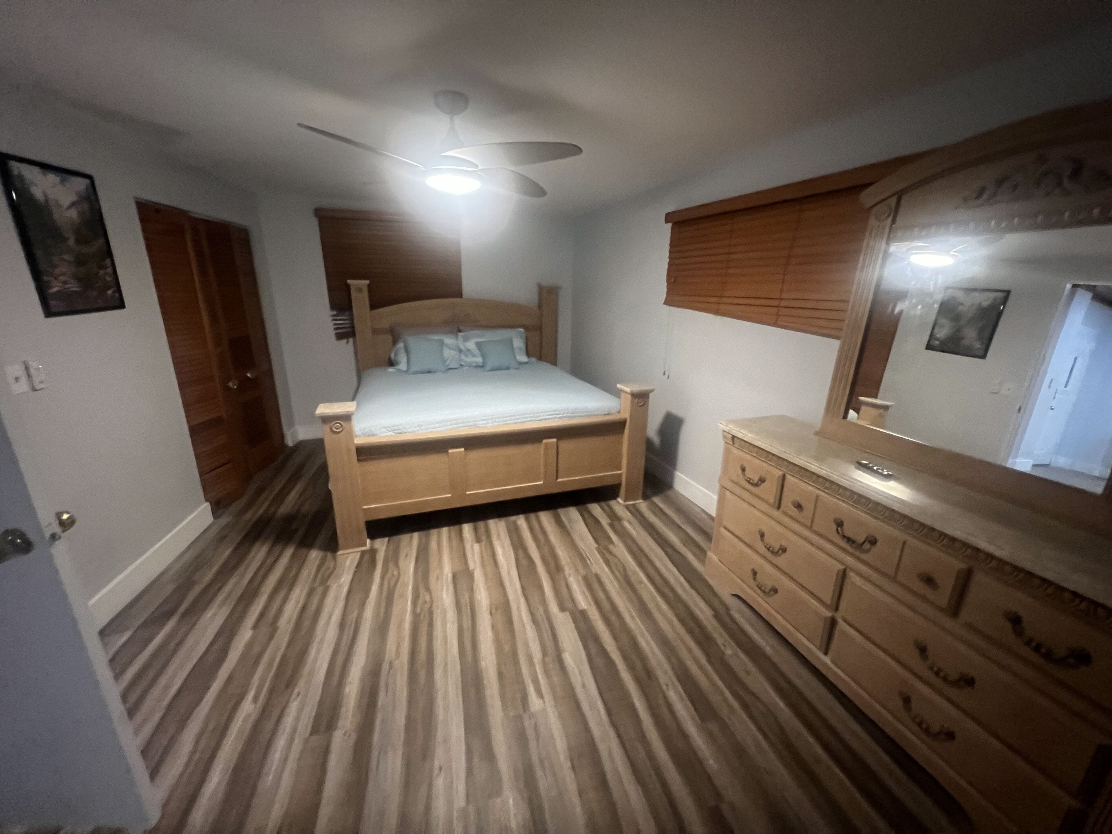 Ein Schlafzimmer mit einem Holzbett, einem Schminktisch, einem Deckenventilator und einem Spiegel.