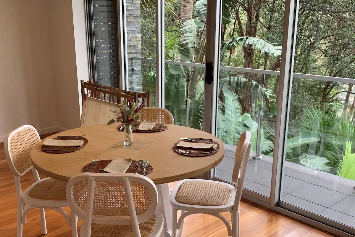 A round dining table with white chairs and a vase of flowers.