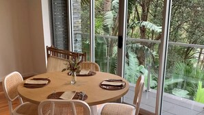 Ein runder Esstisch mit weißen Stühlen und einer Blumenvase.