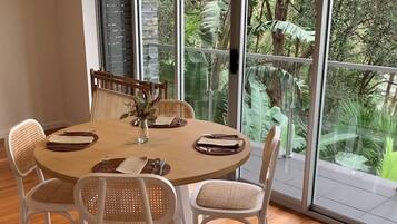 A round dining table with white chairs and a vase of flowers.