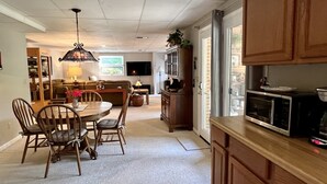 Una cocina amplia con armarios de madera, un comedor con mesa y sillas, y una sala de estar acogedora con un sofá y una televisión.