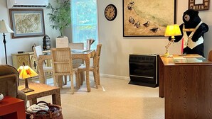 Una sala de estar con una mesa de comedor, sillas, chimenea, un reloj y una estatua de un oso.
