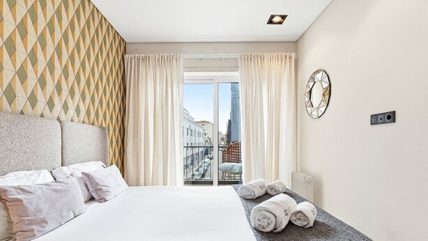 Une chambre d’hôtel avec un lit, une vue sur la ville, une fenêtre avec des rideaux et une horloge murale.
