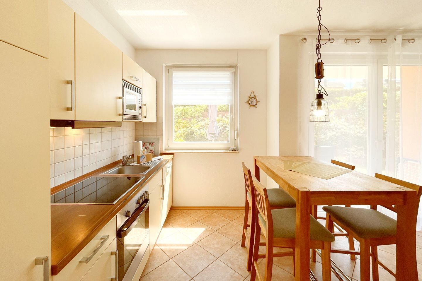 Una cocina con comedor, ventana y lámpara colgante.
