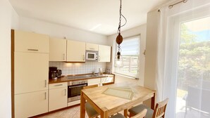 Una cucina funzionale con angolo ristoro, caratterizzata da un tavolo e sedie in legno, un forno a microonde e una lampada a sospensione.