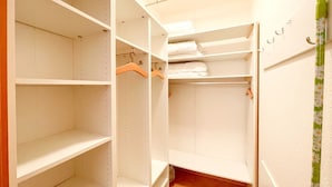 Een inloopkast met open planken en een kledingroede, een houten hanger en een handdoekhouder.