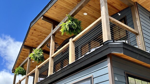 A modern building with large windows, a wooden balcony, and a clear sky. - BRAND NEW, WALK EVERYWHERE! Amazing Views & Luxury in the Heart of Lake Placid (Lake Placid)