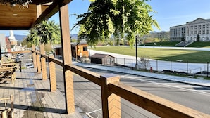 A wooden deck with a view of a building and a grassy field. - BRAND NEW, WALK EVERYWHERE! Amazing Views & Luxury in the Heart of Lake Placid (Lake Placid)