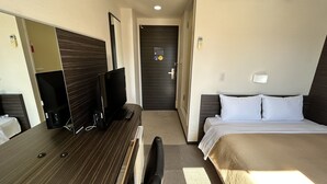 A hotel room with a bed, a desk with a computer, a TV, and a mirror. - Smile Hotel Kokura (Kitakyushu)