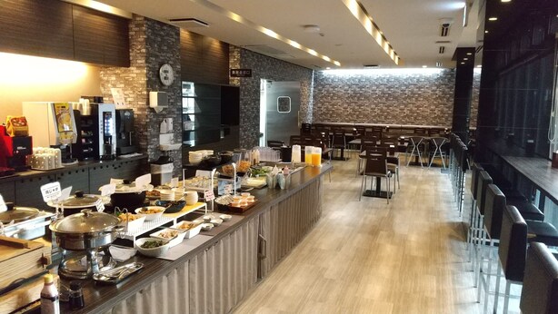 A buffet-style breakfast area with a variety of food options, a clock on the wall, and a seating area with tables and chairs. - Smile Hotel Kokura (Kitakyushu)
