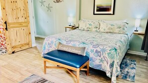 A bedroom with a bed, a bench, a wooden wardrobe, and a wall with starfish and a framed picture.