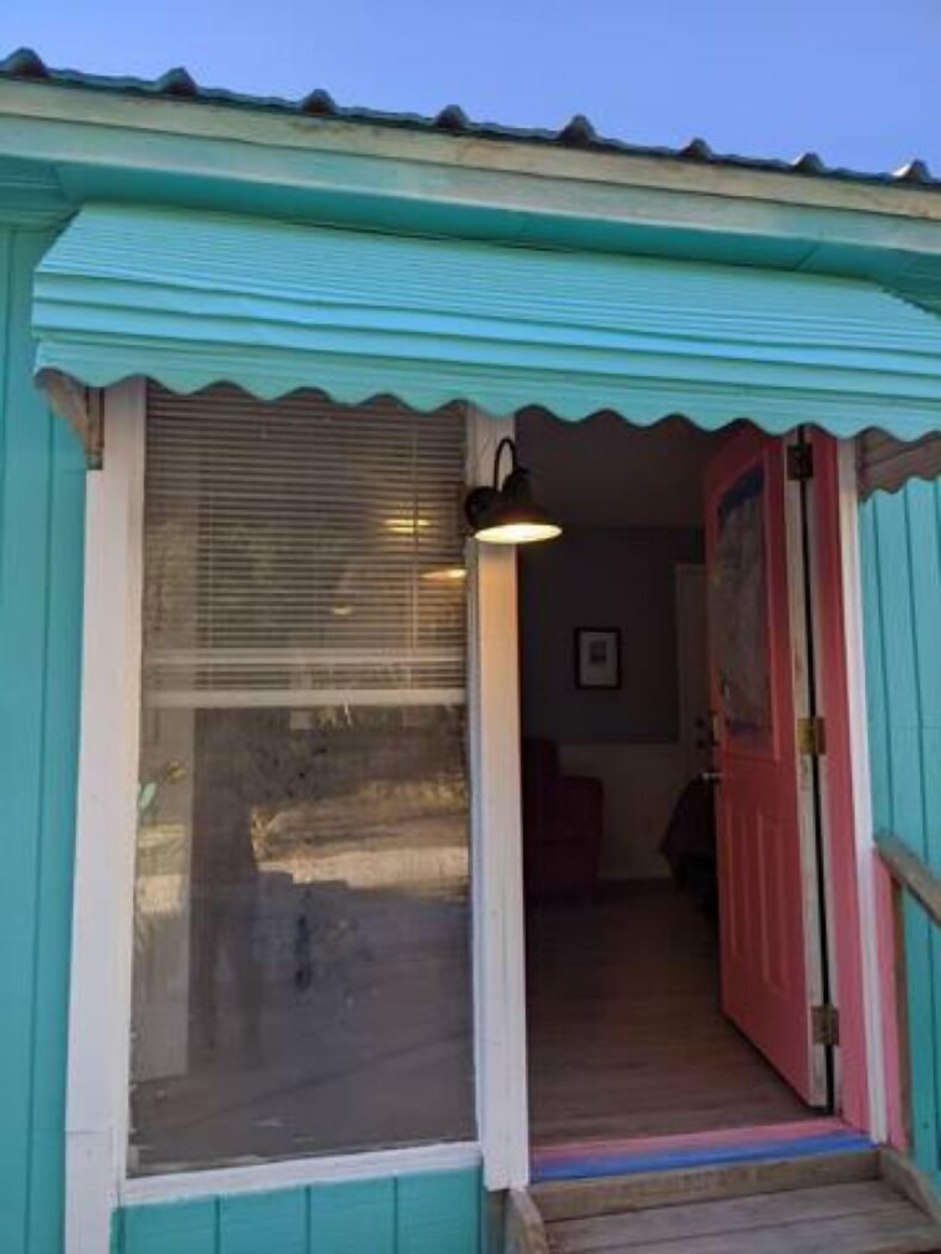Un bâtiment de couleur bleu-vert avec une grande fenêtre et une porte.