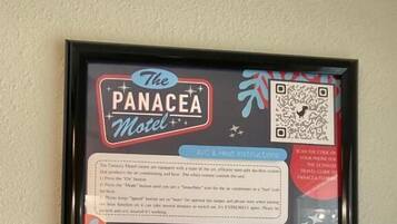 A framed informational poster for The Panacea Motel, detailing amenities like A/C & Heat Instructions, TV, Trash, Pets, Sanitary & Hot Water, and Laundry.