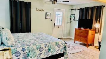 A bedroom with a bed, a dresser, a television, and a ceiling fan.