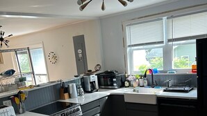 Eine moderne Küche mit einer zentralen Kochinsel, einem Einbauofen und einem Fenster mit Jalousien.