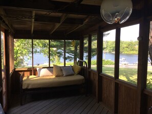 A wooden deck with a bed, large windows, and a view of a lake. - Cozy Hudson Valley Lake Cottage :4 Kayaks + a Canoe, 400 acre Lake (Craryville)
