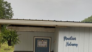 A small building with a blue door, a wooden chair outside, and a sign reading "Mountain Hideaway". - MT. Hideaway 2 bedroom, Lg. parking, .straight across from Buffalo MT. Trail 14 (Delbarton)