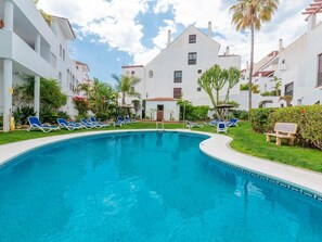 A swimming pool with blue water, surrounded by white buildings with balconies and windows.