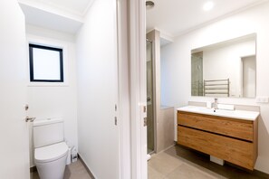 Ein modernes Badezimmer mit Toilette, Dusche und Waschtisch mit Spiegel.