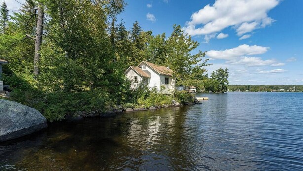 A lakeside cabin with a dock, surrounded by dense trees and calm water. - On the waters edge of Lake Cecebe Tranquility above Muskoka at Rockwynn Cottages (Burk's Falls)