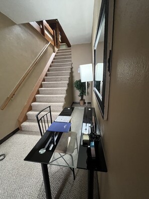 Cozy retreat with a functional layout, featuring a wooden staircase, desk, and comfortable seating area.
