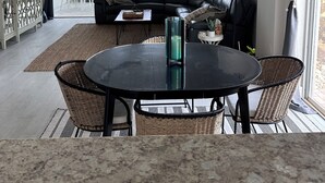 A modern living room with a black leather sofa, a round dining table, and a ceiling light fixture. - Jupiter Dreams at Jupiter Bay! 2 bedroom, 2.5 bath Condo. Close to the beach!  (Jupiter)