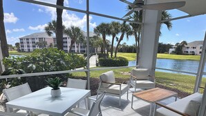 A modern outdoor patio with white furniture, a ceiling fan, and a view of a lake and buildings. - Jupiter Dreams at Jupiter Bay! 2 bedroom, 2.5 bath Condo. Close to the beach!  (Jupiter)